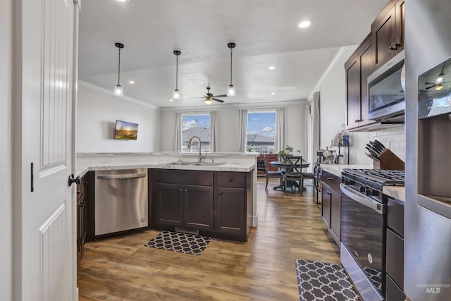kitchen featuring appliances with stainless steel finishes, a sink, ornamental molding, and dark brown cabinetry