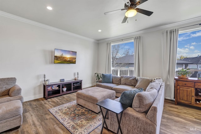 living area with baseboards, ornamental molding, a ceiling fan, and wood finished floors