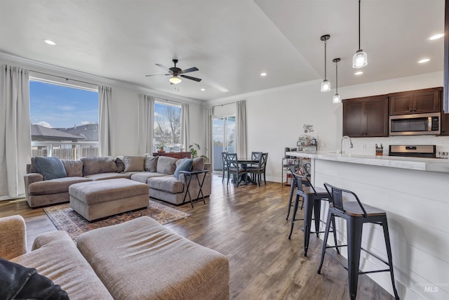 living area featuring recessed lighting, crown molding, a ceiling fan, and wood finished floors