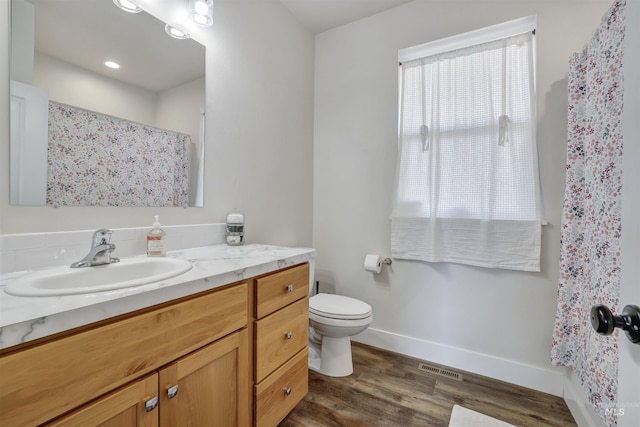 bathroom with visible vents, baseboards, toilet, vanity, and wood finished floors
