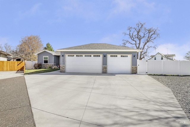 ranch-style home featuring concrete driveway, fence, stone siding, and a gate
