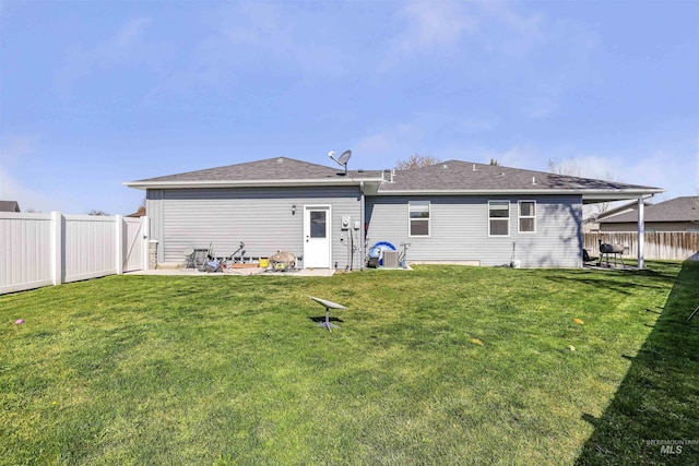 rear view of property with a yard, a fenced backyard, a patio, and roof with shingles