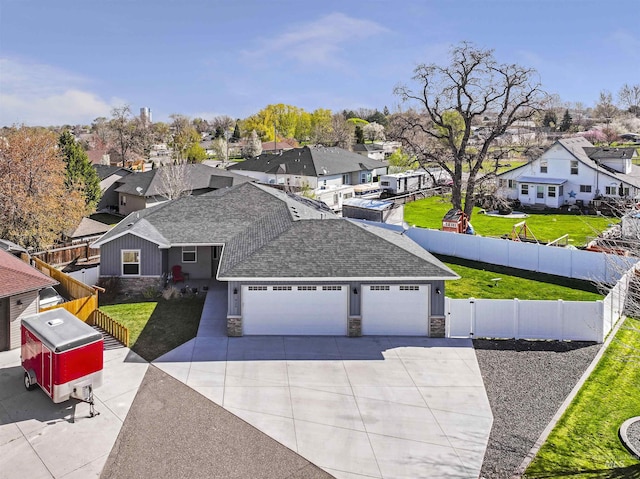 view of front of house with a residential view, fence private yard, driveway, stone siding, and a garage