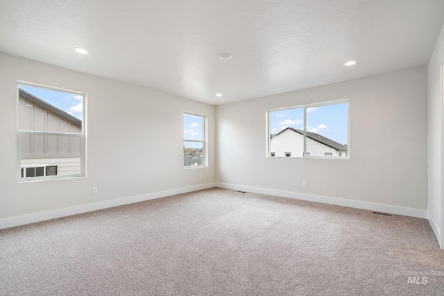 spare room featuring light carpet, visible vents, baseboards, and recessed lighting