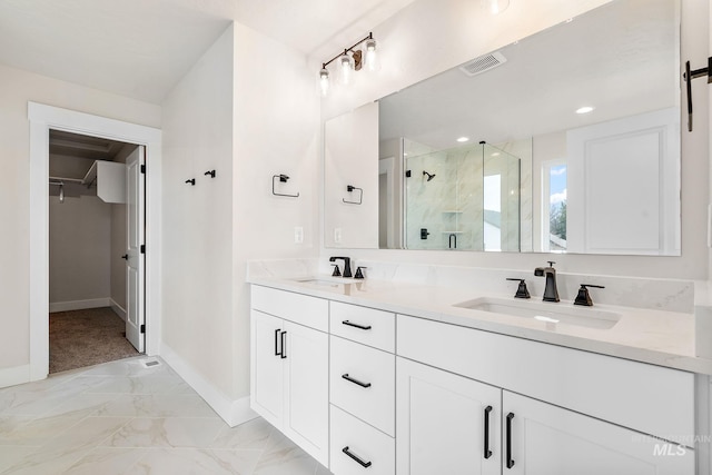 full bathroom with marble finish floor, a stall shower, a sink, and a walk in closet