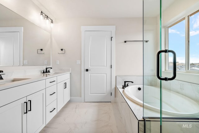 bathroom with marble finish floor, double vanity, a sink, and a bath