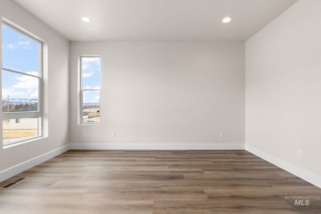 spare room with baseboards, visible vents, wood finished floors, and recessed lighting