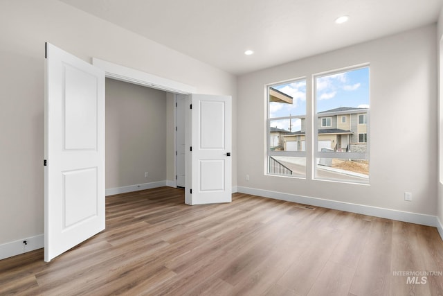 unfurnished bedroom featuring recessed lighting, light wood-style flooring, and baseboards