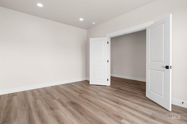 spare room featuring light wood-type flooring, baseboards, and recessed lighting