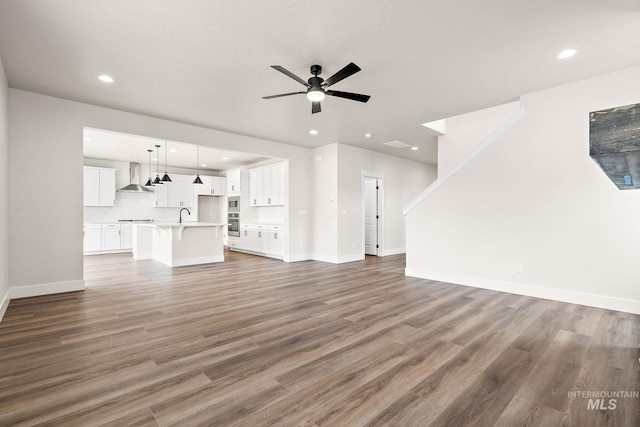 unfurnished living room featuring recessed lighting, ceiling fan, baseboards, and wood finished floors