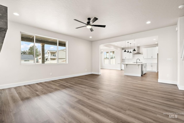 unfurnished living room with a healthy amount of sunlight, a sink, and wood finished floors