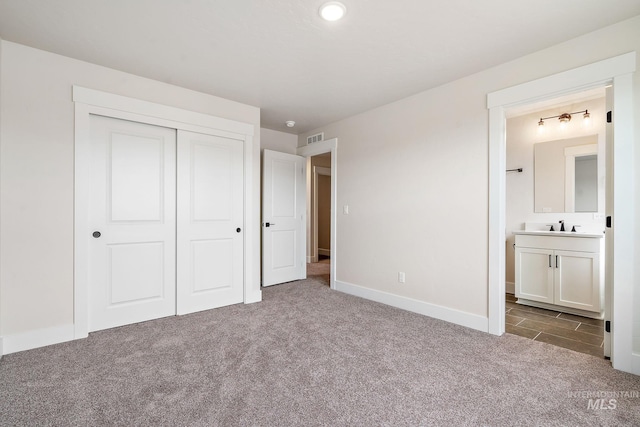 unfurnished bedroom with connected bathroom, carpet floors, a sink, visible vents, and a closet