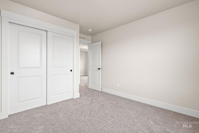 unfurnished bedroom featuring visible vents, a closet, baseboards, and carpet flooring