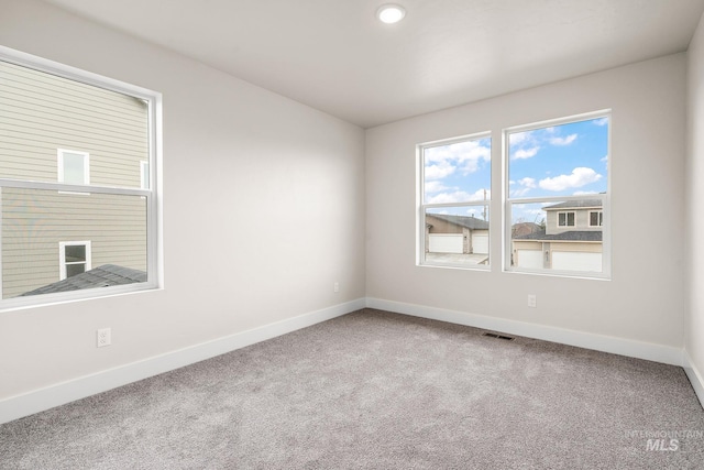 carpeted spare room featuring visible vents and baseboards