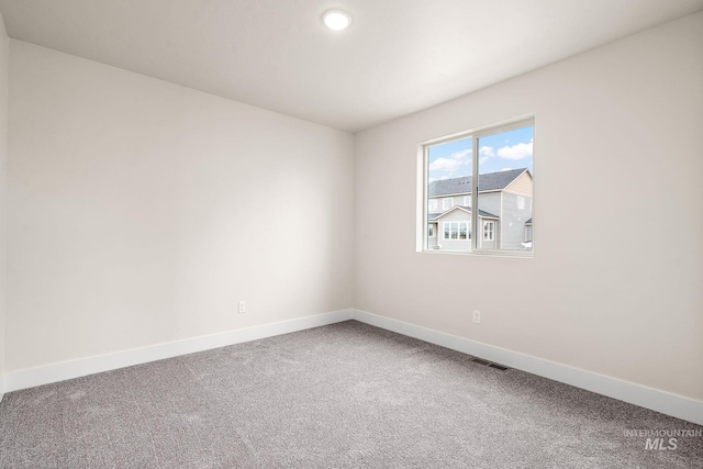 carpeted spare room featuring baseboards and visible vents