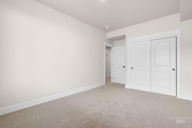 unfurnished bedroom with carpet floors, visible vents, baseboards, and a closet