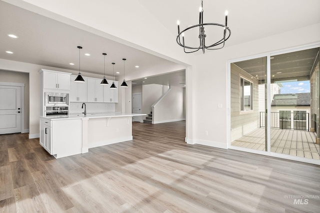 kitchen featuring light countertops, light wood-style flooring, an inviting chandelier, appliances with stainless steel finishes, and white cabinets