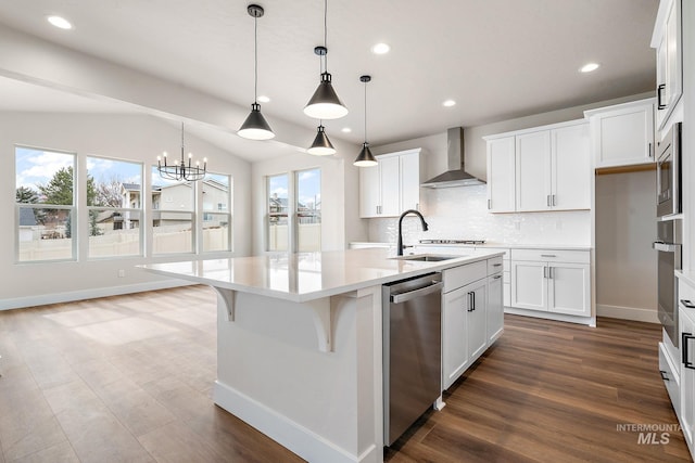 kitchen with light countertops, backsplash, appliances with stainless steel finishes, a sink, and wall chimney exhaust hood