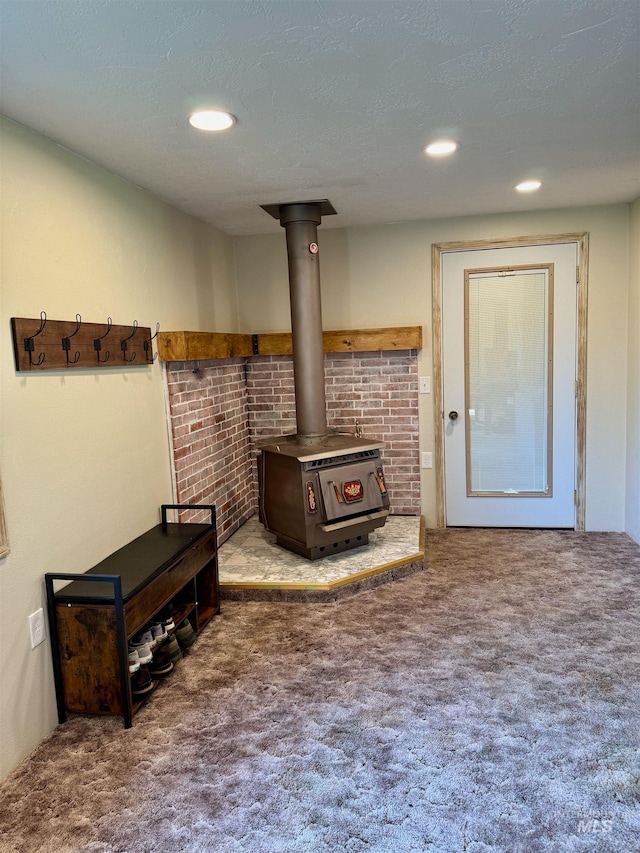 interior space featuring a textured ceiling, carpet, and a wood stove