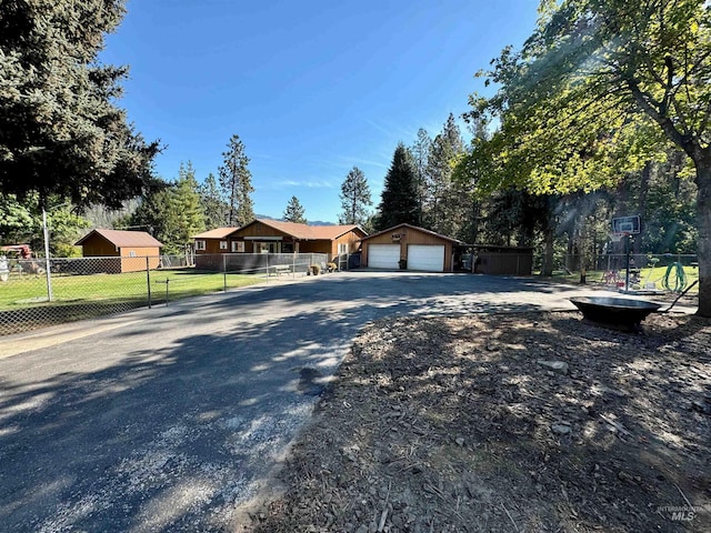 ranch-style house with a garage, a front lawn, and an outbuilding