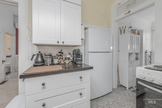 kitchen featuring white fridge, stove, white cabinetry, and backsplash