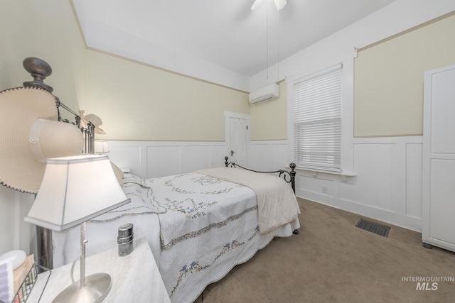 carpeted bedroom featuring an AC wall unit and ceiling fan