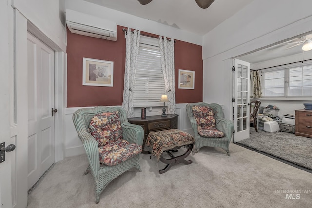 sitting room featuring a wall mounted air conditioner, ceiling fan, and light colored carpet