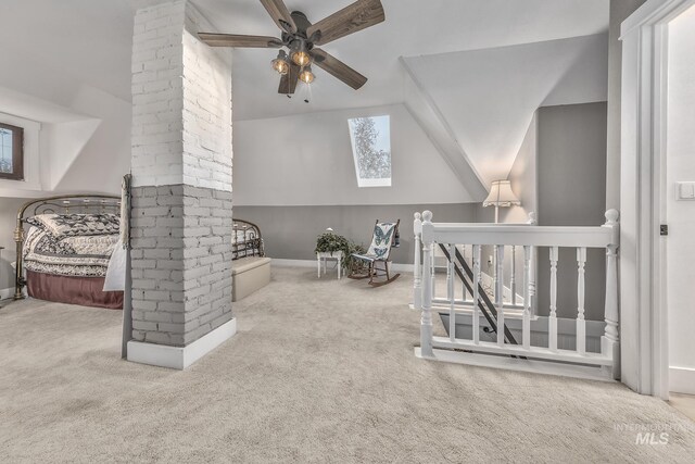 carpeted bedroom featuring ornate columns, ceiling fan, and vaulted ceiling with skylight