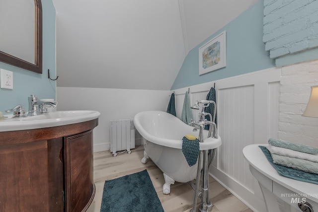 bathroom featuring vanity, lofted ceiling, radiator, a tub to relax in, and wood-type flooring