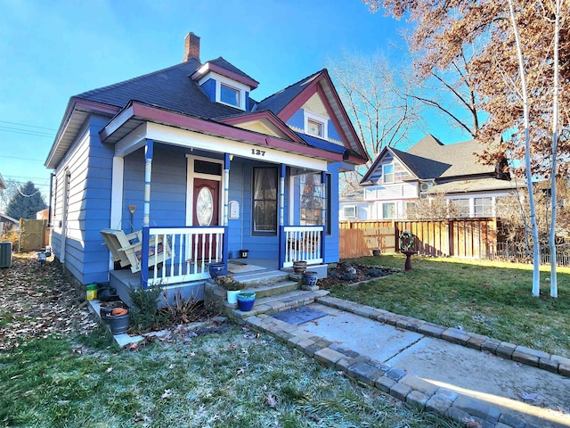 bungalow-style house featuring central AC, a porch, and a front yard