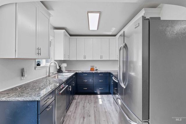 kitchen with appliances with stainless steel finishes, white cabinets, and blue cabinets