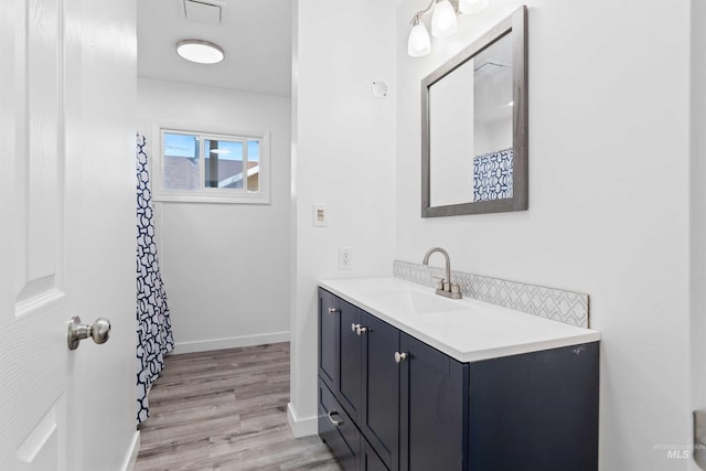 bathroom with wood finished floors, vanity, baseboards, and a shower with shower curtain