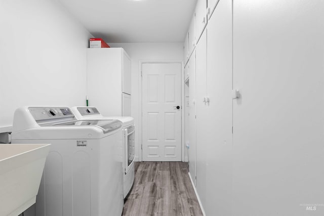 laundry room featuring washing machine and dryer and light wood-style floors