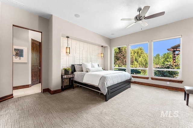 bedroom featuring light carpet, baseboards, and ceiling fan