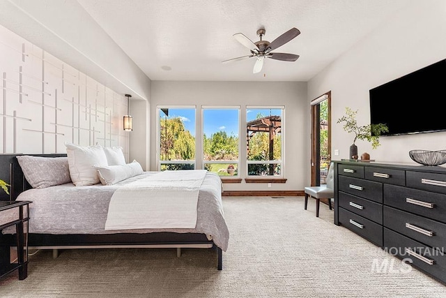 bedroom featuring light carpet, access to exterior, and a ceiling fan