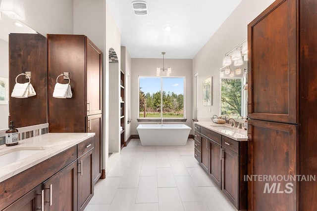 full bathroom with a freestanding bath, two vanities, and tile patterned floors