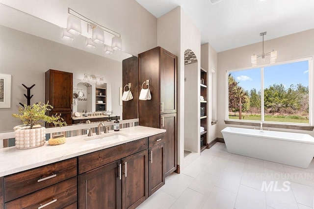 bathroom featuring vanity, a freestanding bath, and tile patterned flooring