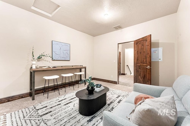 carpeted living area with attic access, baseboards, and a textured ceiling