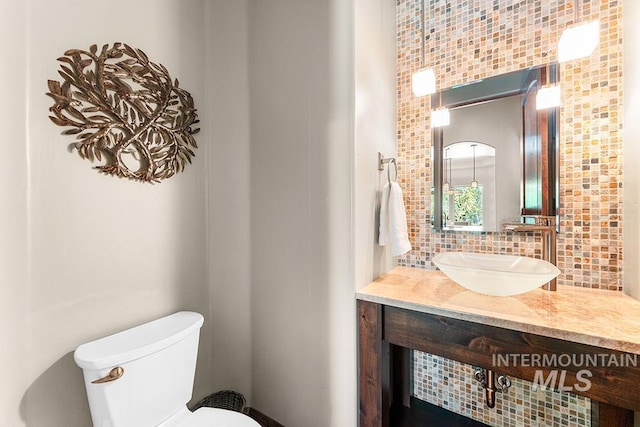 bathroom featuring decorative backsplash, toilet, and vanity