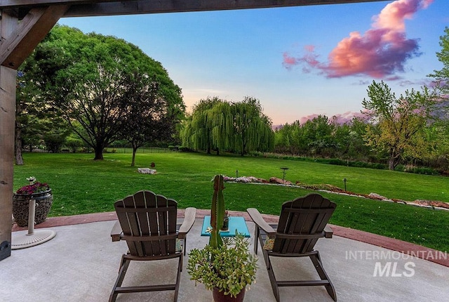 patio terrace at dusk featuring a lawn