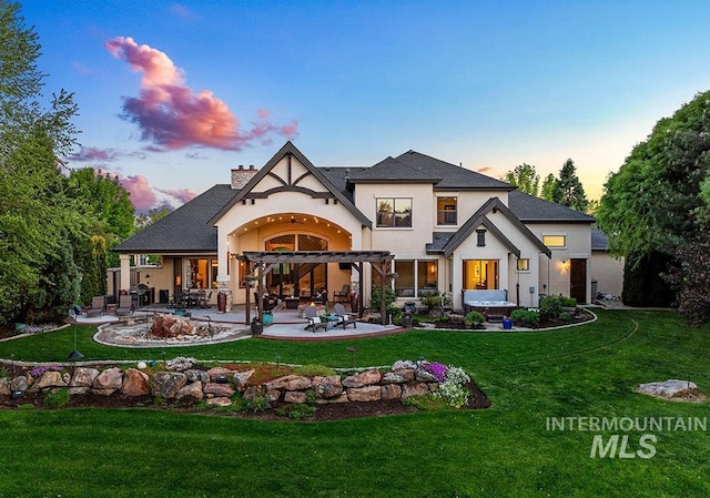 rear view of house with a patio area, stucco siding, a yard, and a pergola