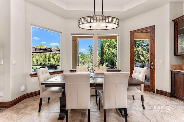 dining area featuring a tray ceiling and baseboards