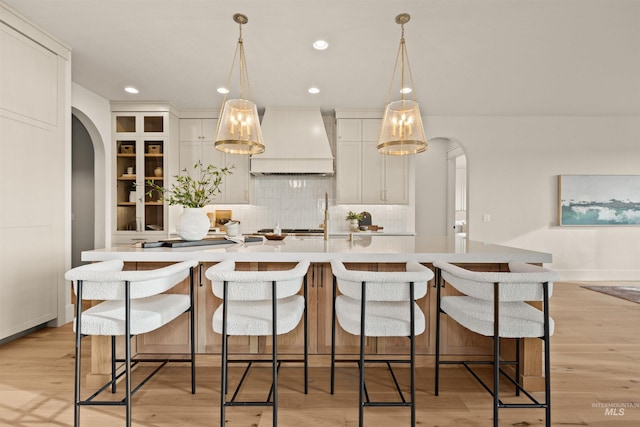 11473 N 17th Way, Boise, ID 83714 - kitchen with custom exhaust hood, arched walkways, an island with sink, decorative backsplash, and light countertops