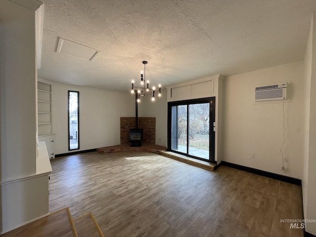 unfurnished living room with a wood stove, a wall mounted AC, hardwood / wood-style floors, and plenty of natural light