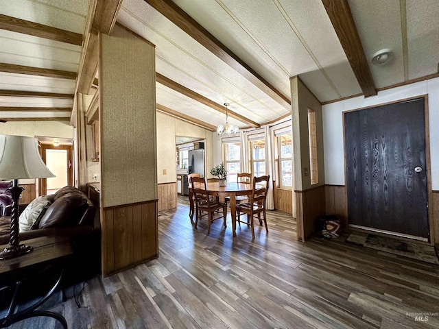 dining room featuring vaulted ceiling with beams, a chandelier, wooden walls, and wood-type flooring