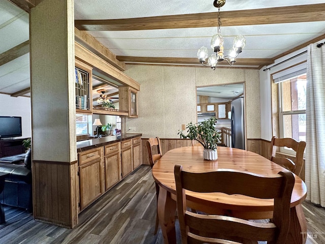 dining space with a chandelier, vaulted ceiling with beams, dark hardwood / wood-style floors, and wood walls