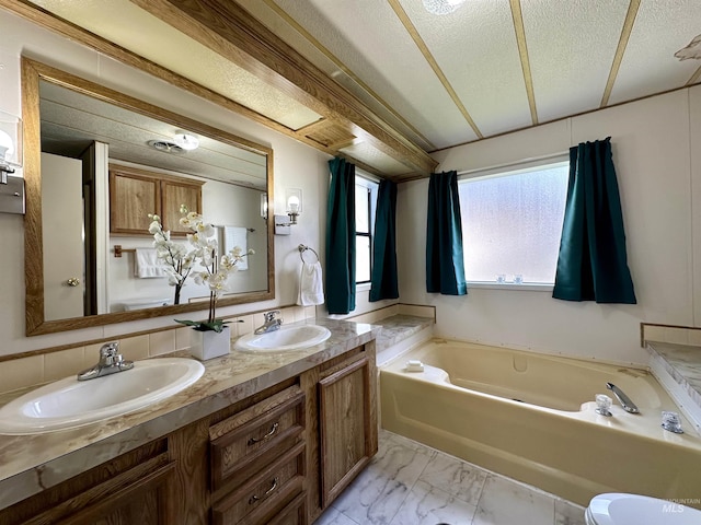 bathroom featuring vanity, a textured ceiling, backsplash, and a tub to relax in