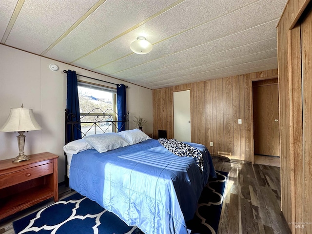 bedroom with dark hardwood / wood-style floors and wood walls