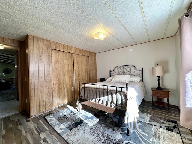 bedroom featuring dark hardwood / wood-style flooring, wooden walls, and a closet