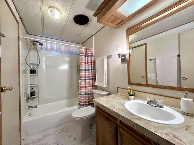 full bathroom with vanity, toilet, shower / bath combo with shower curtain, and a textured ceiling